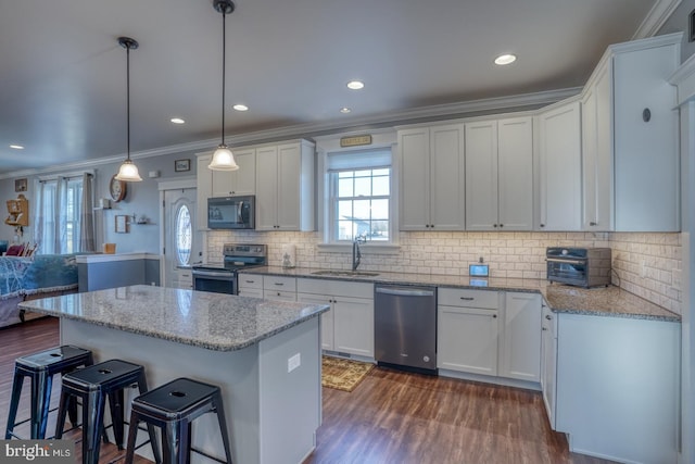 kitchen with sink, white cabinetry, crown molding, hanging light fixtures, and stainless steel appliances