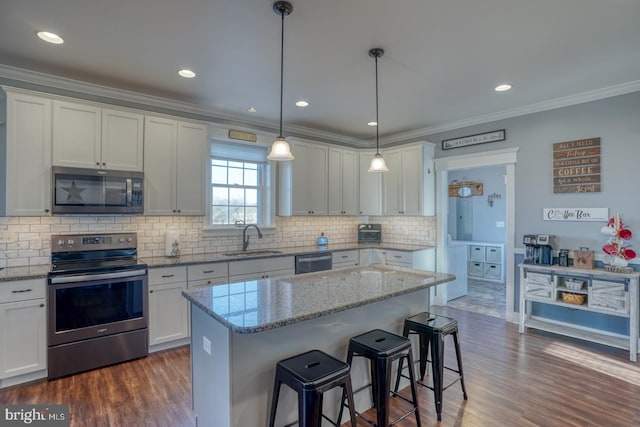 kitchen with appliances with stainless steel finishes, sink, a kitchen island, and white cabinets