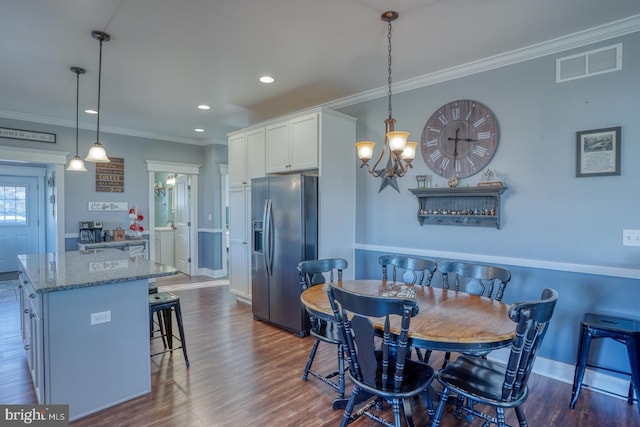 dining room with crown molding, dark hardwood / wood-style floors, and an inviting chandelier