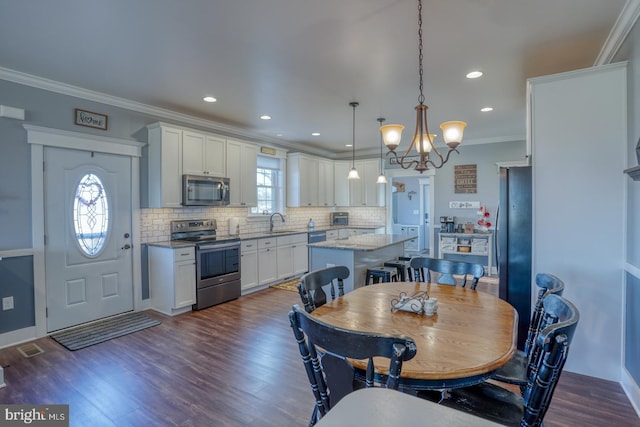 dining space featuring sink, a wealth of natural light, ornamental molding, and dark hardwood / wood-style floors