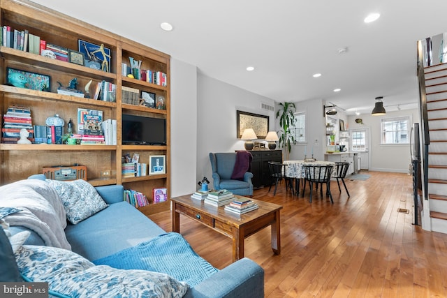 living room with recessed lighting, wood finished floors, visible vents, and stairs