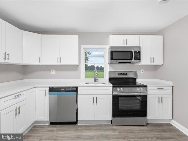 kitchen featuring white cabinetry, sink, stainless steel appliances, and light wood-type flooring