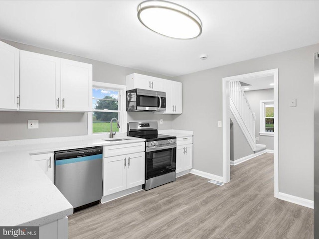 kitchen featuring sink, light wood-type flooring, white cabinets, and appliances with stainless steel finishes