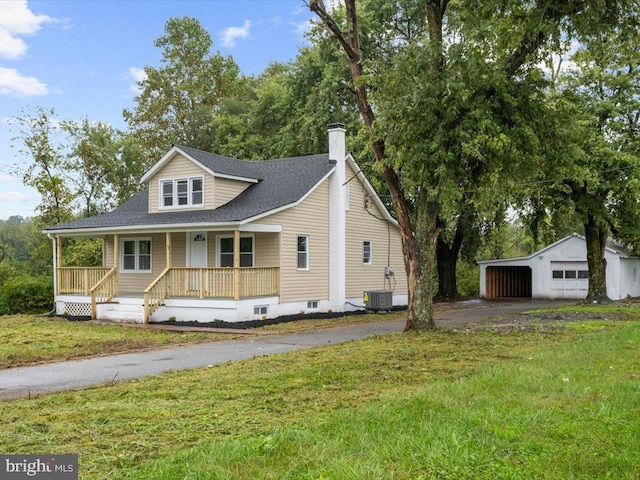 view of front of house featuring a front yard, central AC unit, a garage, covered porch, and an outbuilding