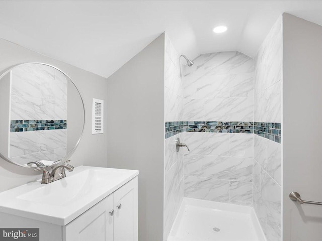 bathroom with vanity, vaulted ceiling, and a tile shower