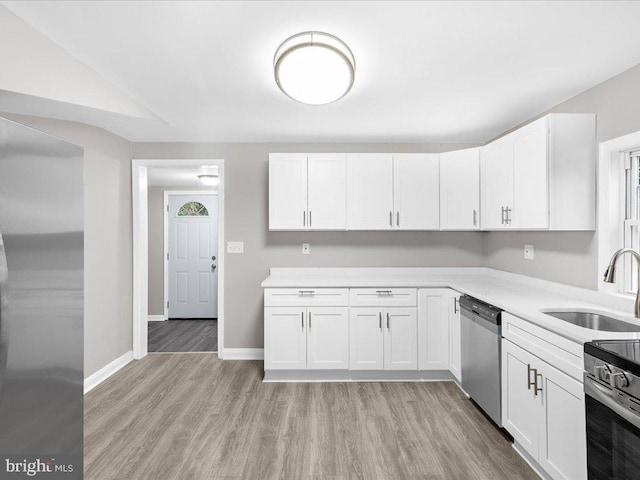 kitchen featuring white cabinetry, appliances with stainless steel finishes, sink, and light hardwood / wood-style flooring