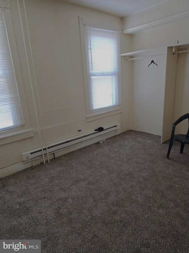 carpeted spare room featuring a baseboard heating unit