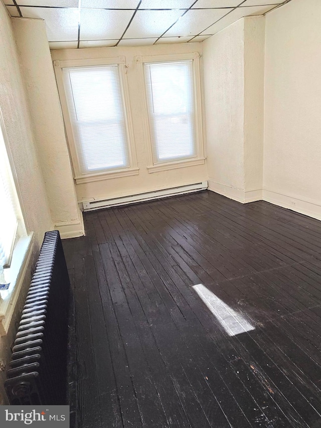 unfurnished room with a drop ceiling, dark wood-type flooring, and baseboard heating