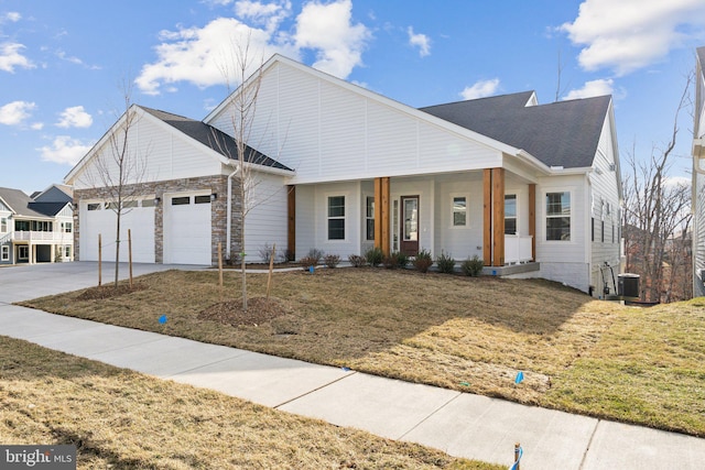 view of front of property with a garage, central air condition unit, covered porch, and a front lawn