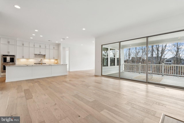 unfurnished living room with sink and light hardwood / wood-style flooring