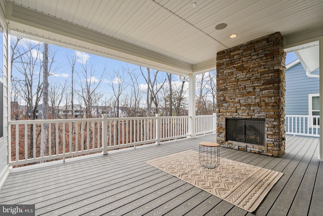 wooden deck with an outdoor stone fireplace