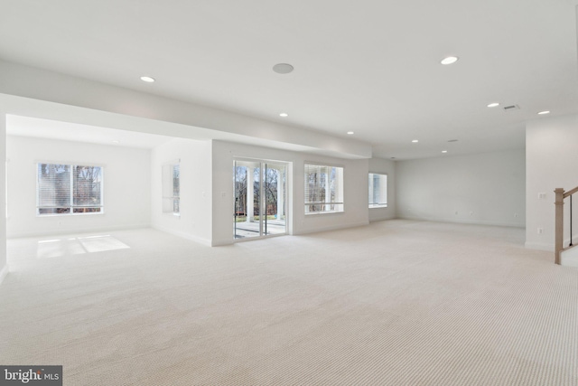 unfurnished living room featuring light carpet and a wealth of natural light