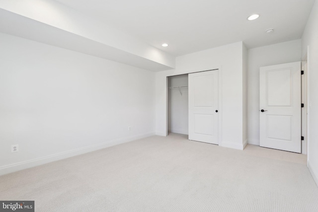 unfurnished bedroom with light carpet and a closet