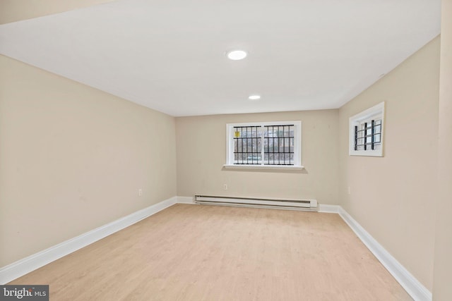 empty room featuring a baseboard radiator and light hardwood / wood-style floors