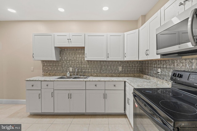 kitchen with light tile patterned flooring, sink, white cabinets, black range with electric cooktop, and light stone countertops