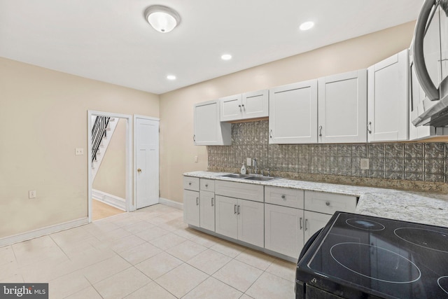 kitchen featuring sink, light stone counters, electric range, decorative backsplash, and white cabinets