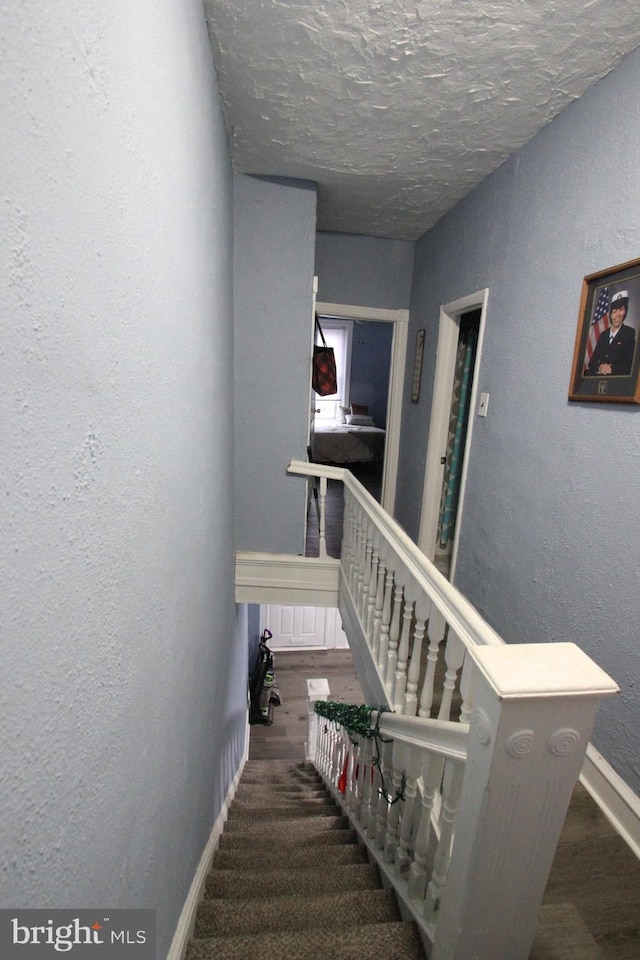 stairs with wood-type flooring and a textured ceiling