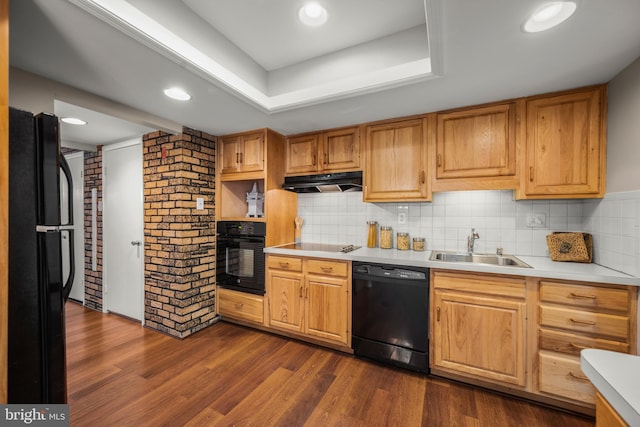 kitchen with dark hardwood / wood-style flooring, black appliances, sink, a tray ceiling, and decorative backsplash