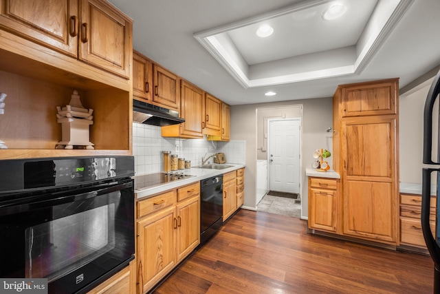 kitchen featuring dark hardwood / wood-style flooring, black appliances, sink, backsplash, and a raised ceiling