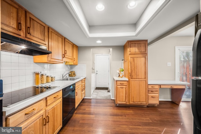 kitchen with dark wood-type flooring, black appliances, backsplash, a tray ceiling, and sink