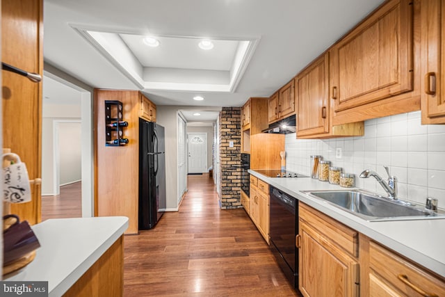 kitchen with black appliances, a raised ceiling, backsplash, sink, and dark hardwood / wood-style floors