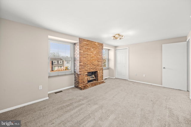 unfurnished living room with a brick fireplace, carpet, and plenty of natural light