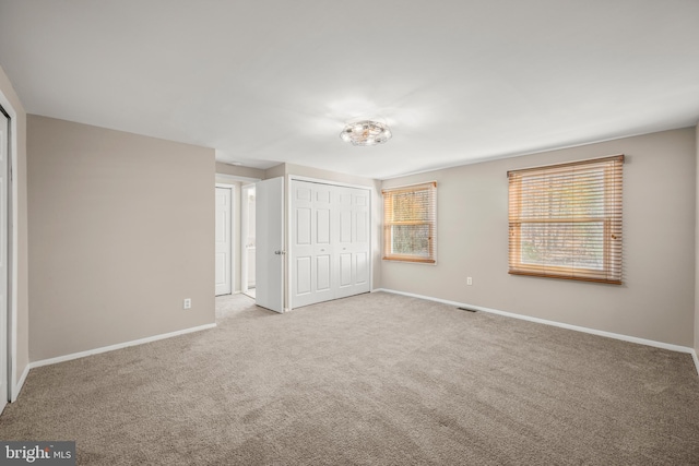 unfurnished bedroom featuring light carpet and a closet