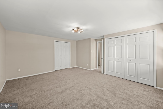 unfurnished bedroom featuring multiple closets and light colored carpet