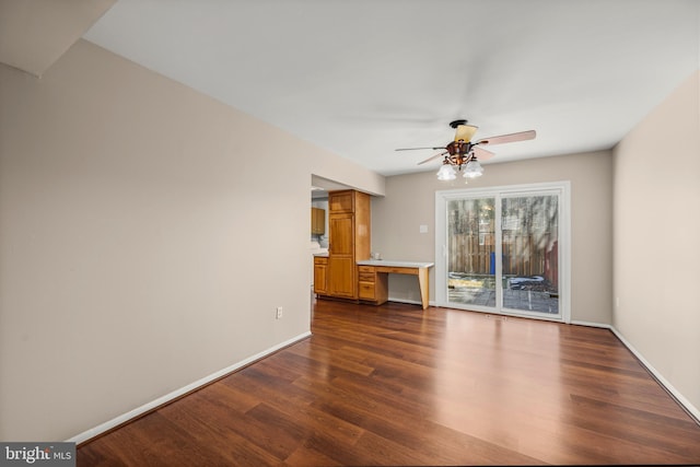 unfurnished living room featuring ceiling fan and dark wood-type flooring