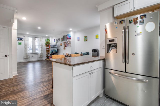 kitchen with dark wood-type flooring, white cabinetry, stainless steel fridge with ice dispenser, kitchen peninsula, and dark stone counters