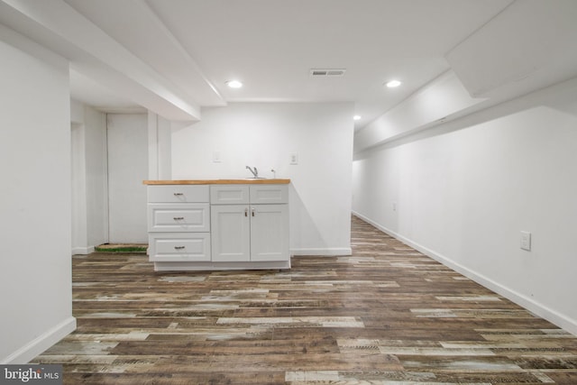 bar with dark wood-type flooring, wood counters, sink, and white cabinets