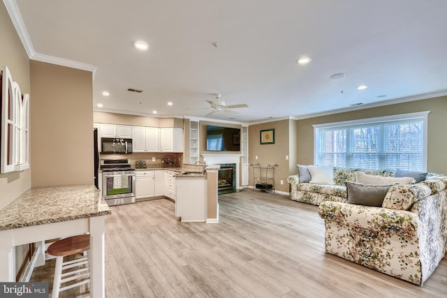 kitchen featuring crown molding, white cabinetry, light stone countertops, gas stove, and kitchen peninsula