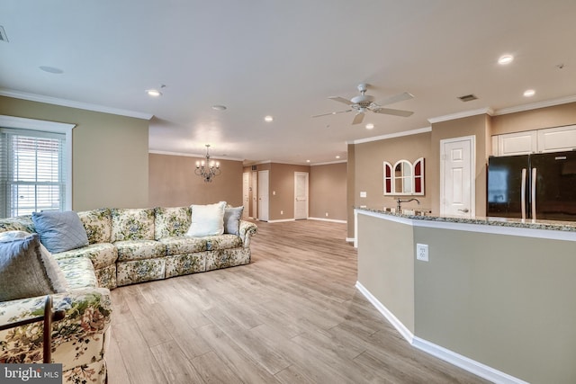 living room featuring ornamental molding, ceiling fan with notable chandelier, and light wood-type flooring