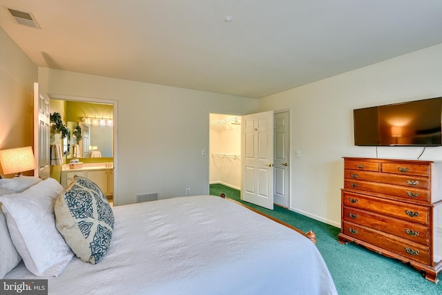 carpeted bedroom with ensuite bath and a walk in closet