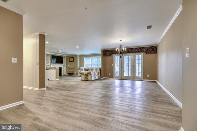 unfurnished living room with crown molding, ceiling fan with notable chandelier, and light hardwood / wood-style flooring