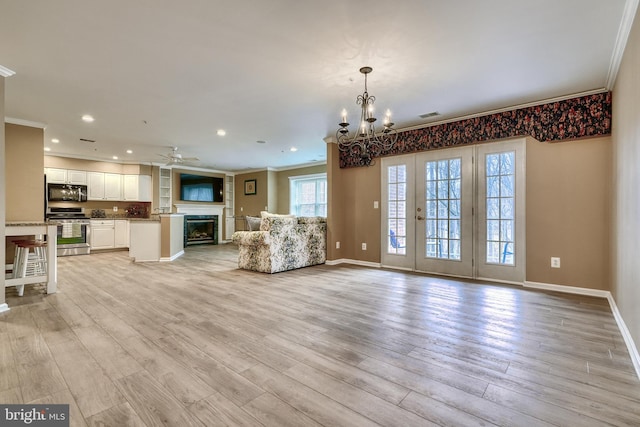 unfurnished living room with crown molding, ceiling fan with notable chandelier, light hardwood / wood-style floors, and french doors