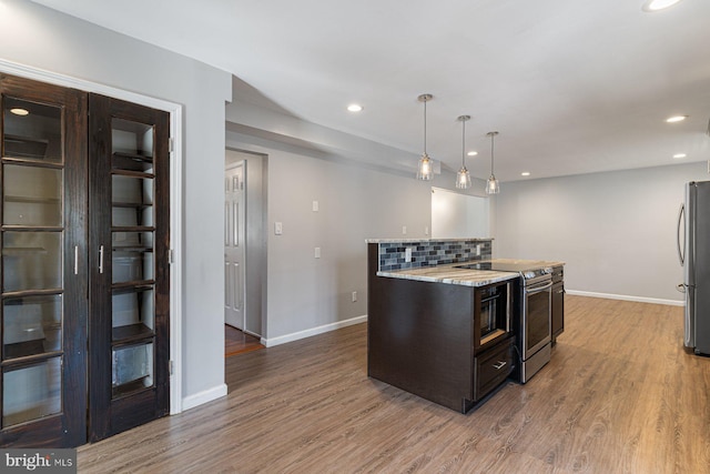 1762 Red Oak Ln, Waldorf, MD 20601 - kitchen with dark brown cabinets, a center island, appliances with stainless steel finishes, wood finished floors, and backsplash