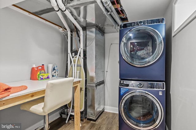 clothes washing area featuring dark wood-type flooring and stacked washer and clothes dryer