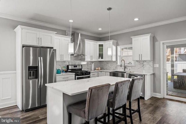 kitchen featuring sink, appliances with stainless steel finishes, hanging light fixtures, a center island, and wall chimney exhaust hood