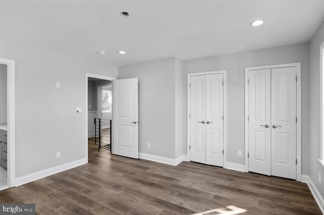 unfurnished bedroom with two closets and dark wood-type flooring