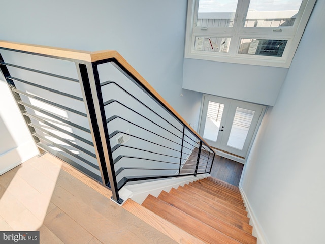 stairway with french doors and hardwood / wood-style flooring