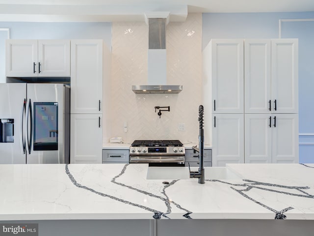 kitchen featuring light stone counters, stainless steel appliances, and wall chimney exhaust hood