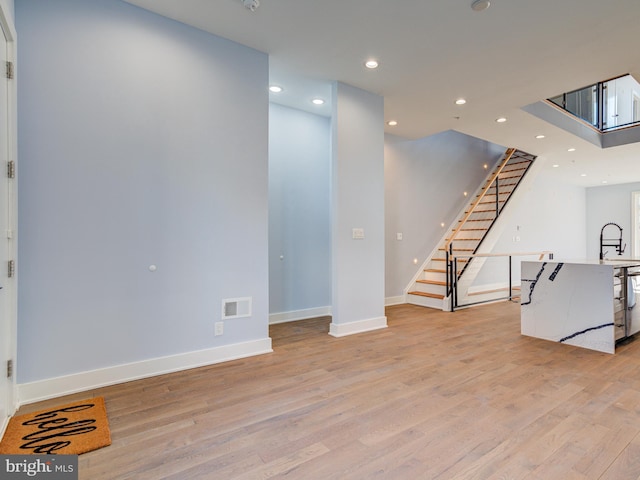 basement with light hardwood / wood-style flooring and sink