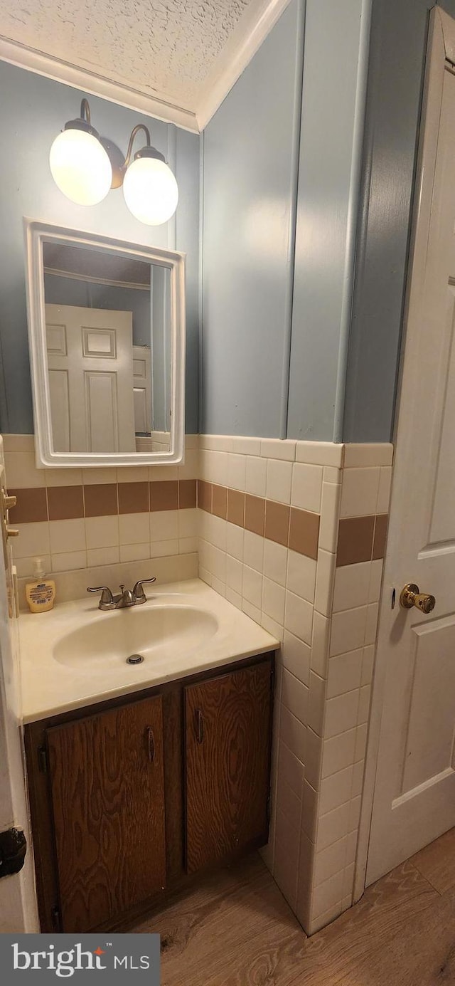 bathroom featuring a textured ceiling, wood finished floors, vanity, and tile walls