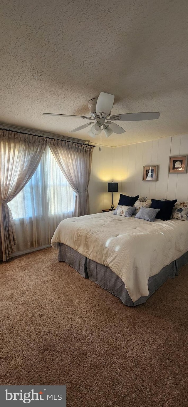 carpeted bedroom with ceiling fan and a textured ceiling