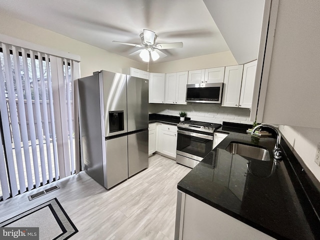 kitchen featuring sink, white cabinets, decorative backsplash, stainless steel appliances, and light hardwood / wood-style flooring