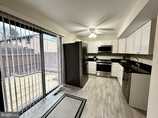 kitchen with white cabinetry, stainless steel appliances, sink, and light wood-type flooring