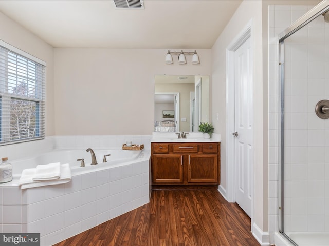 bathroom featuring hardwood / wood-style flooring, vanity, and separate shower and tub