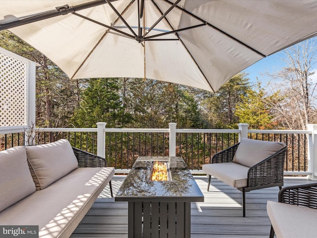 wooden terrace with an outdoor living space with a fire pit