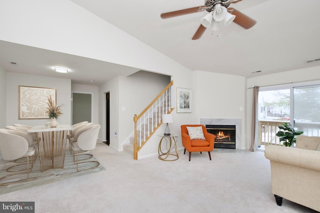 sitting room featuring ceiling fan, lofted ceiling, a high end fireplace, and light carpet